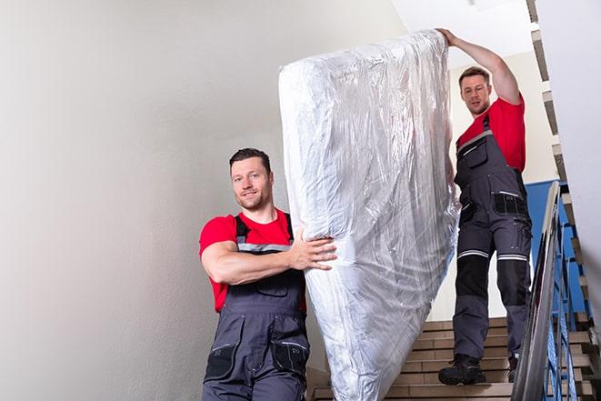 two people carrying a box spring down a staircase in Oak Park, IL